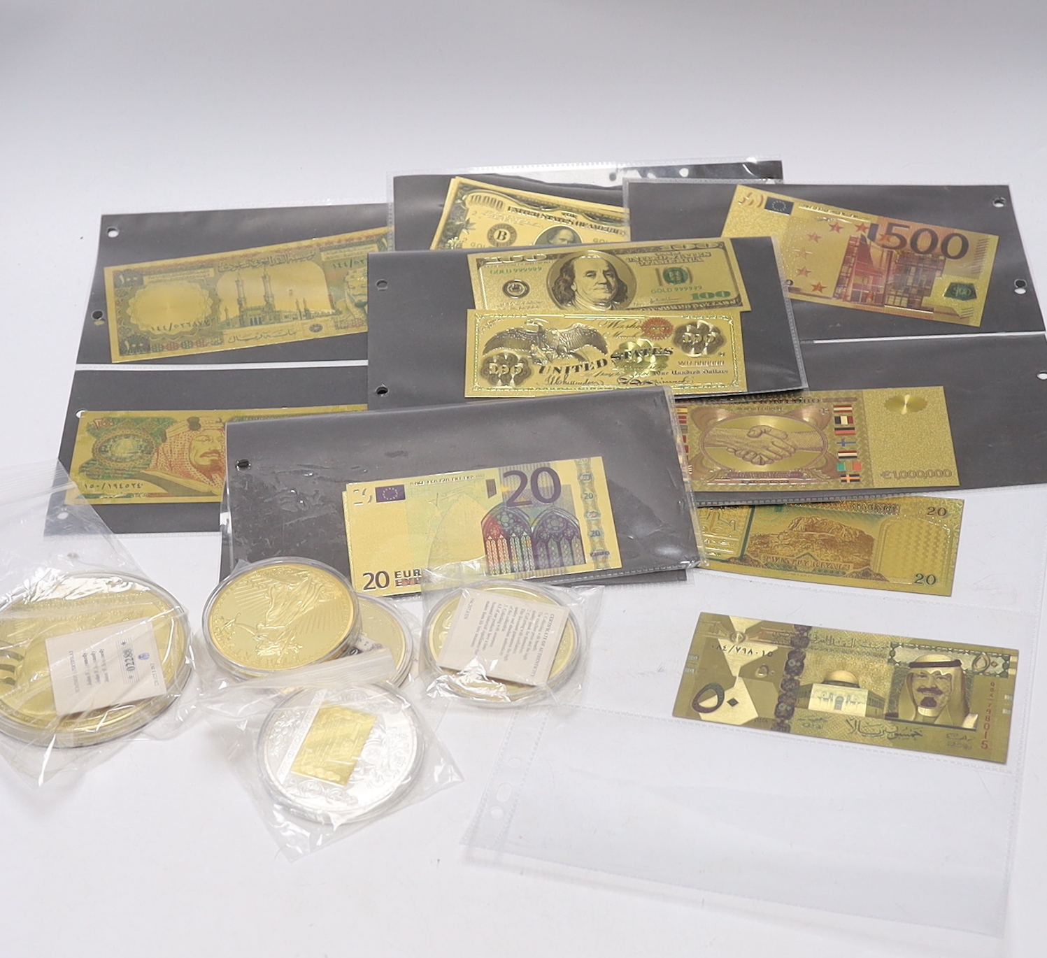 A collection of gold plated medallions and bank notes